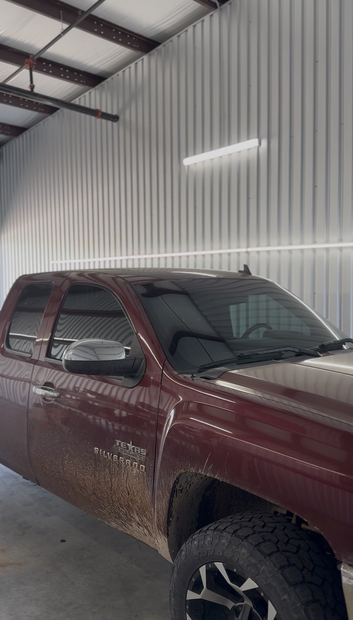 Maroon Chevrolet Silverado with tinted windows inside the shop