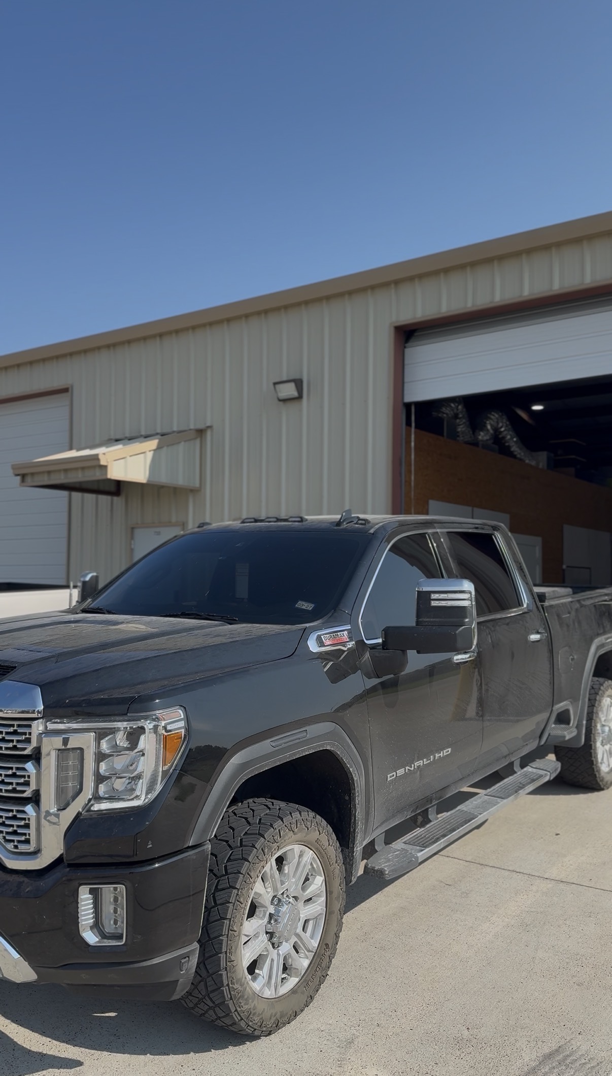 Gray GMC Sierra with tinted windows outside the shop