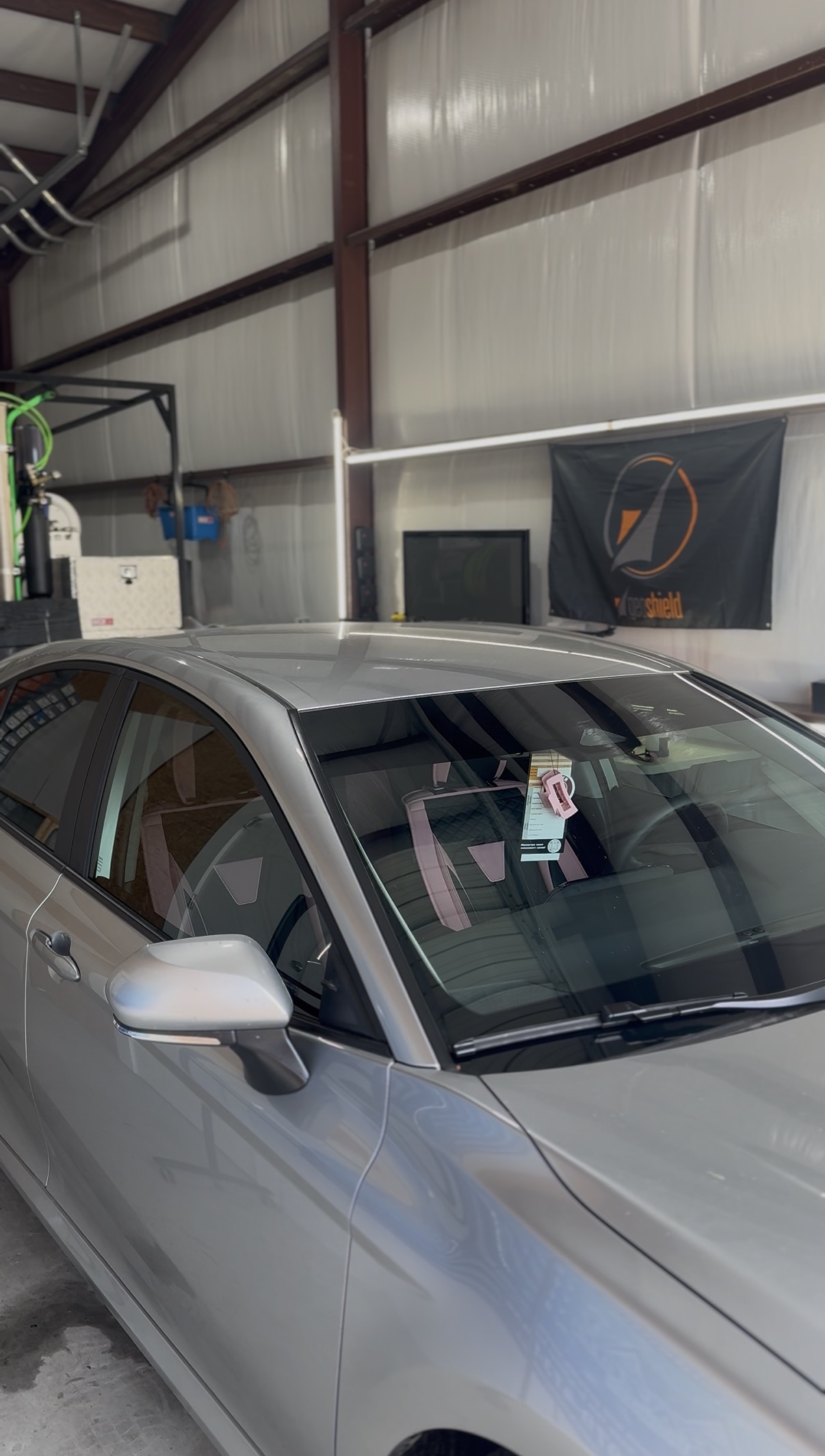 Silver car with tinted windshield inside the shop