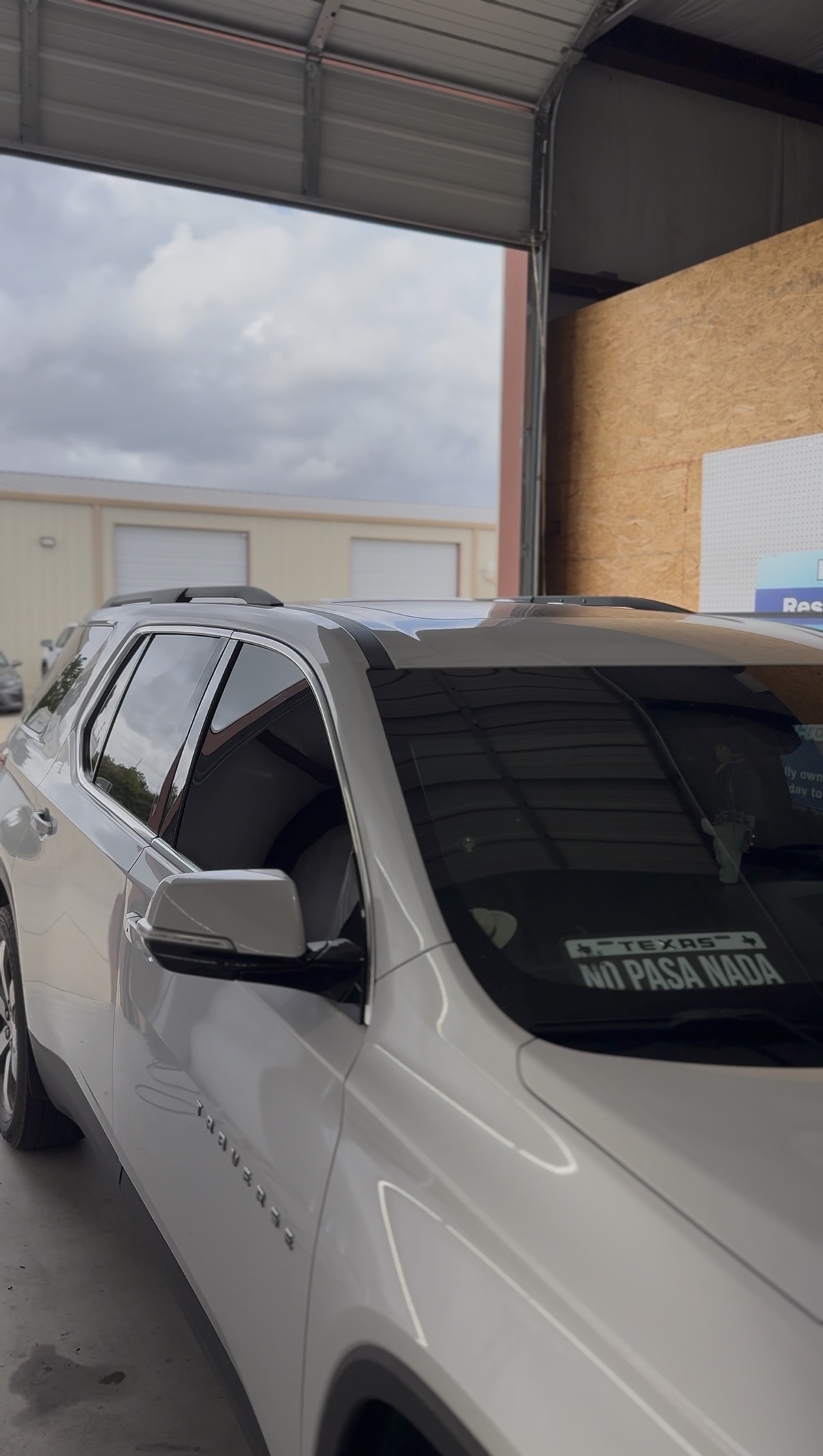 White SUV with tinted windows parked under the shop awning