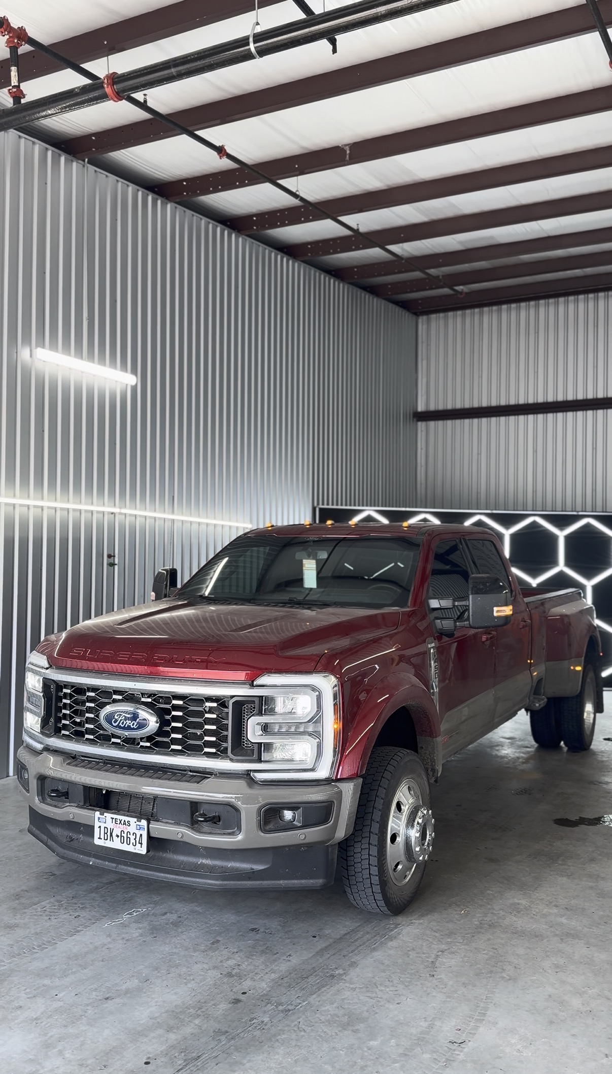Maroon Ford F-350 dually with tinted windows inside the shop