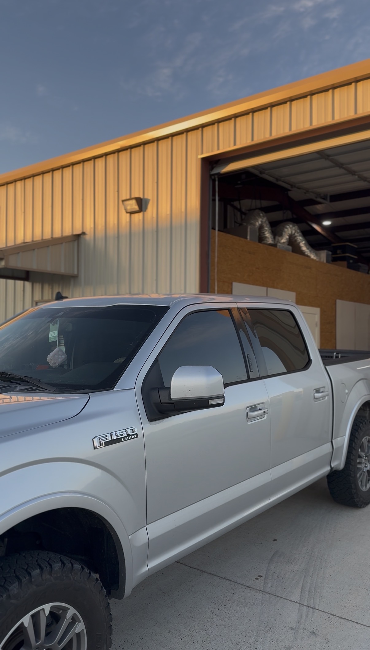 Silver Ford F-150 with tinted windows outside the shop