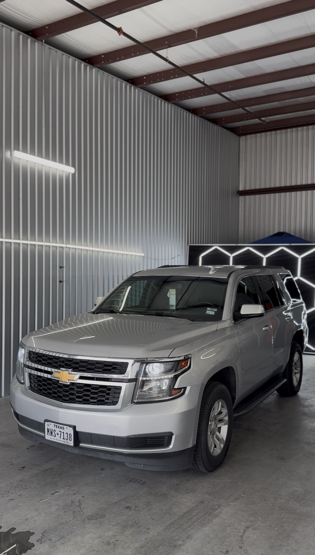 Silver Chevrolet Suburban with tinted windows inside the shop