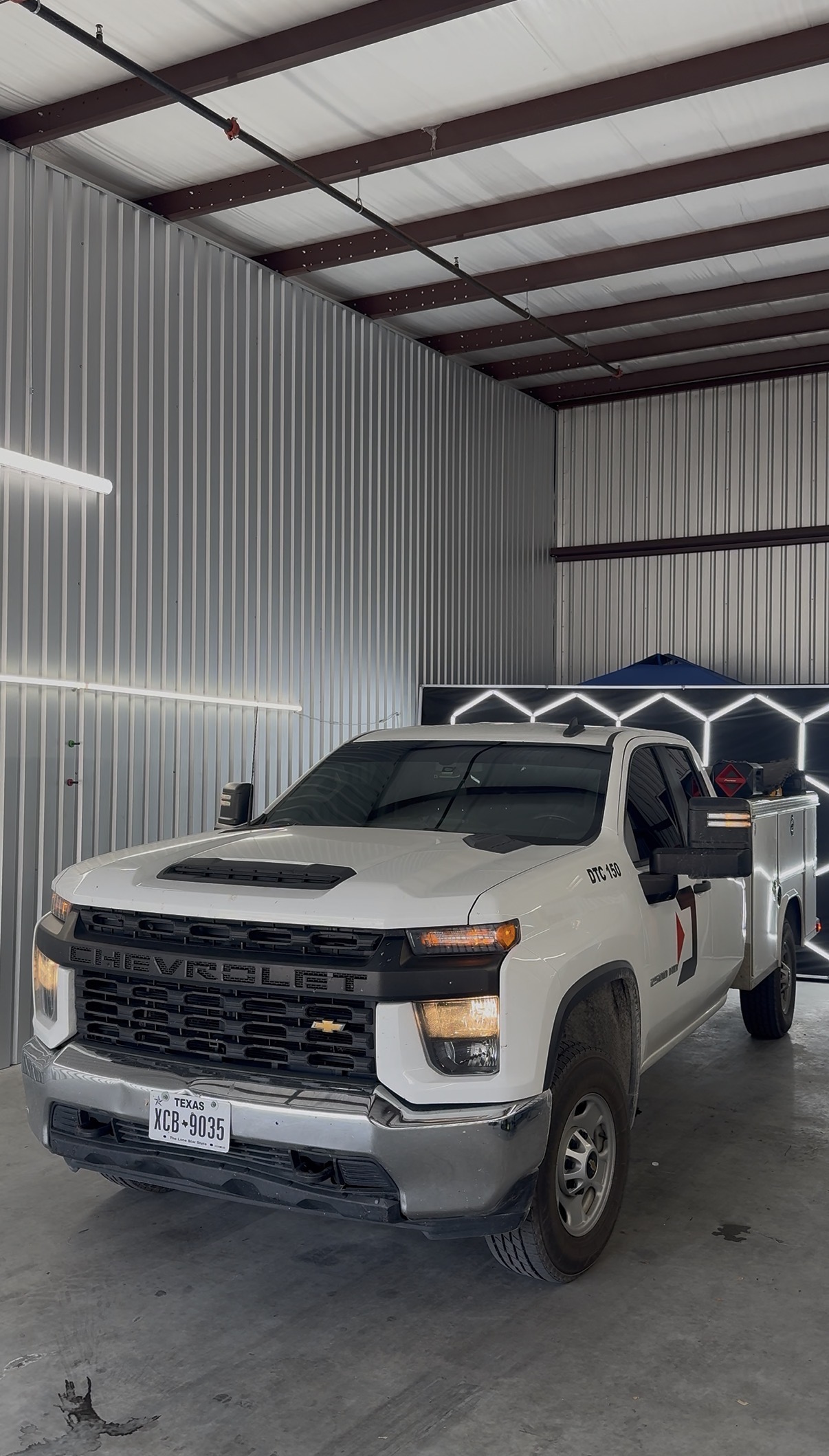 White Chevrolet Silverado with tinted windows inside the shop